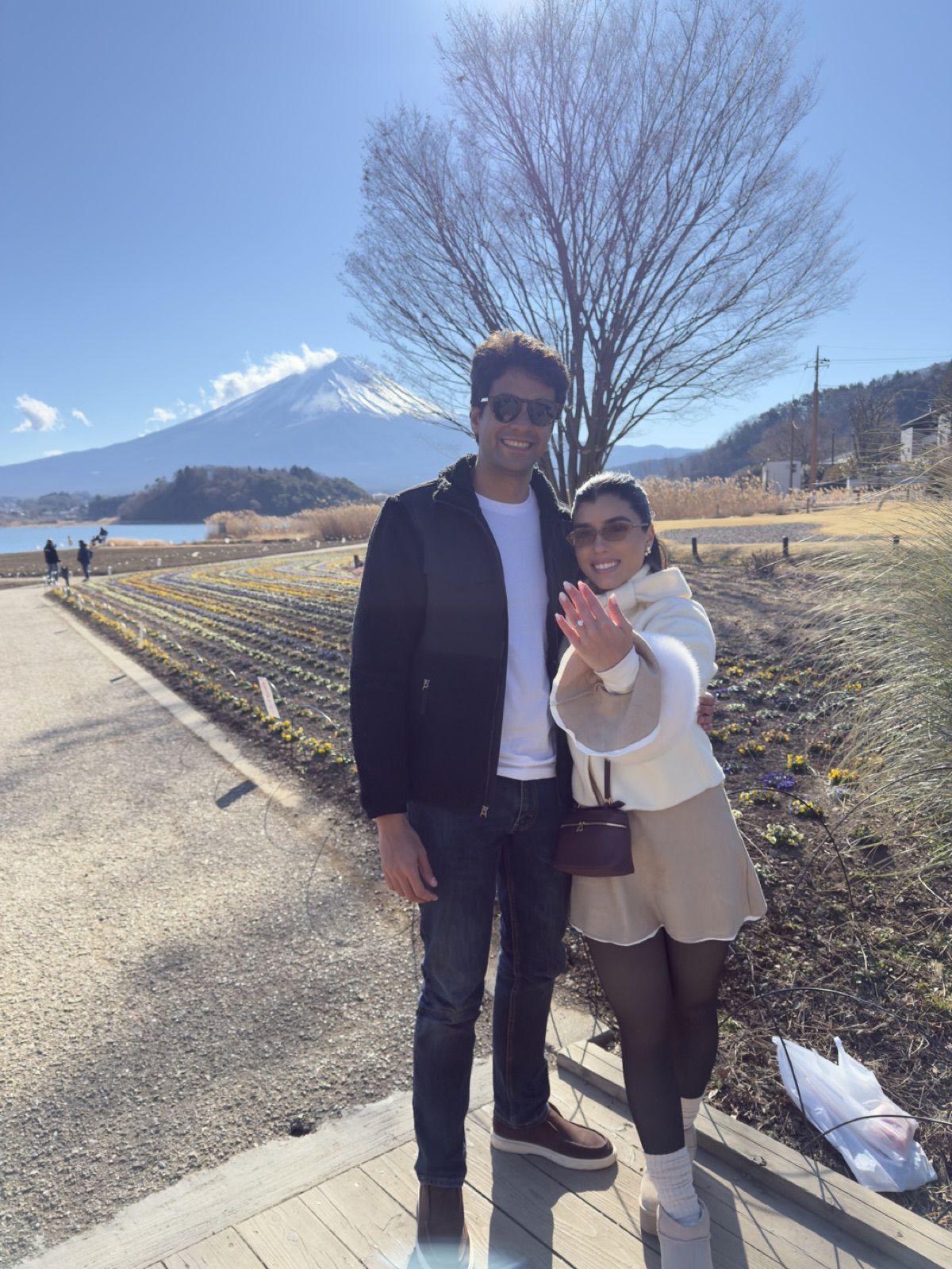 Gabriela e José em pé, ela mostrando a aliança, com o Monte Fuji ao fundo